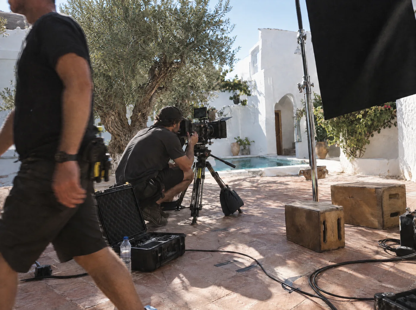 Our crew on set: an operator crouched at the camera in a sunlit courtyard
